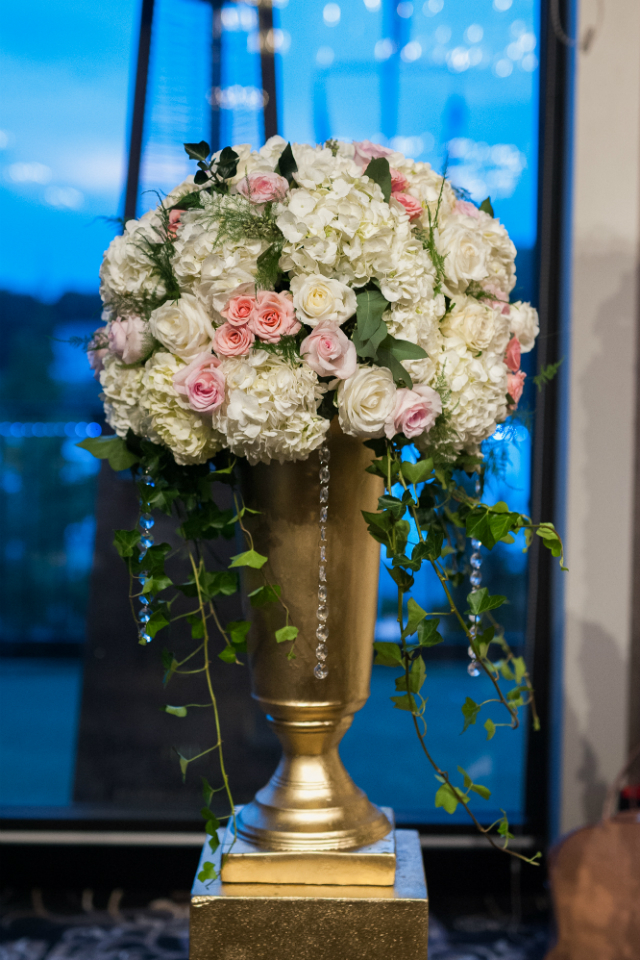 Tall wedding centerpiece with white and light pink flowers in a gold vase by Stapleton Floral Design
