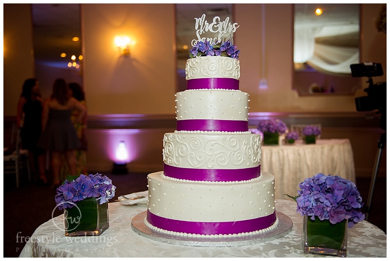 white wedding cake with purple accents and purple flowers