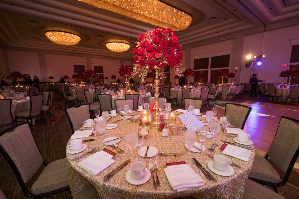 Tall centerpiece with red roses in a gold vase by Stapleton Floral Design