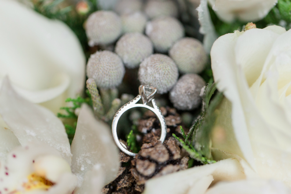 Winter bouquet with cream roses, pinecones, and snow by Stapleton Floral Design