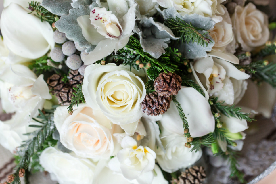 Winter bouquet with cream roses, pinecones, and snow by Stapleton Floral Design