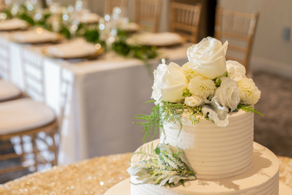 Simple white wedding cake with white flowers on top and accents of greenery