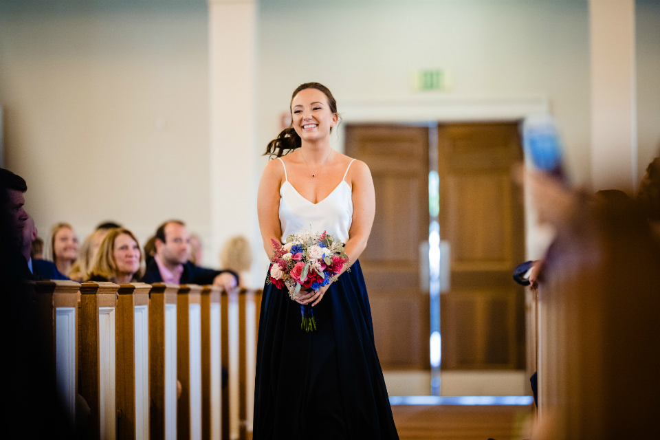 Smiling maid of honor walking down the aisle