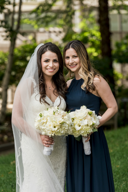 Bride and bridesmaid holding elegant bouquet in hues of white and cream
