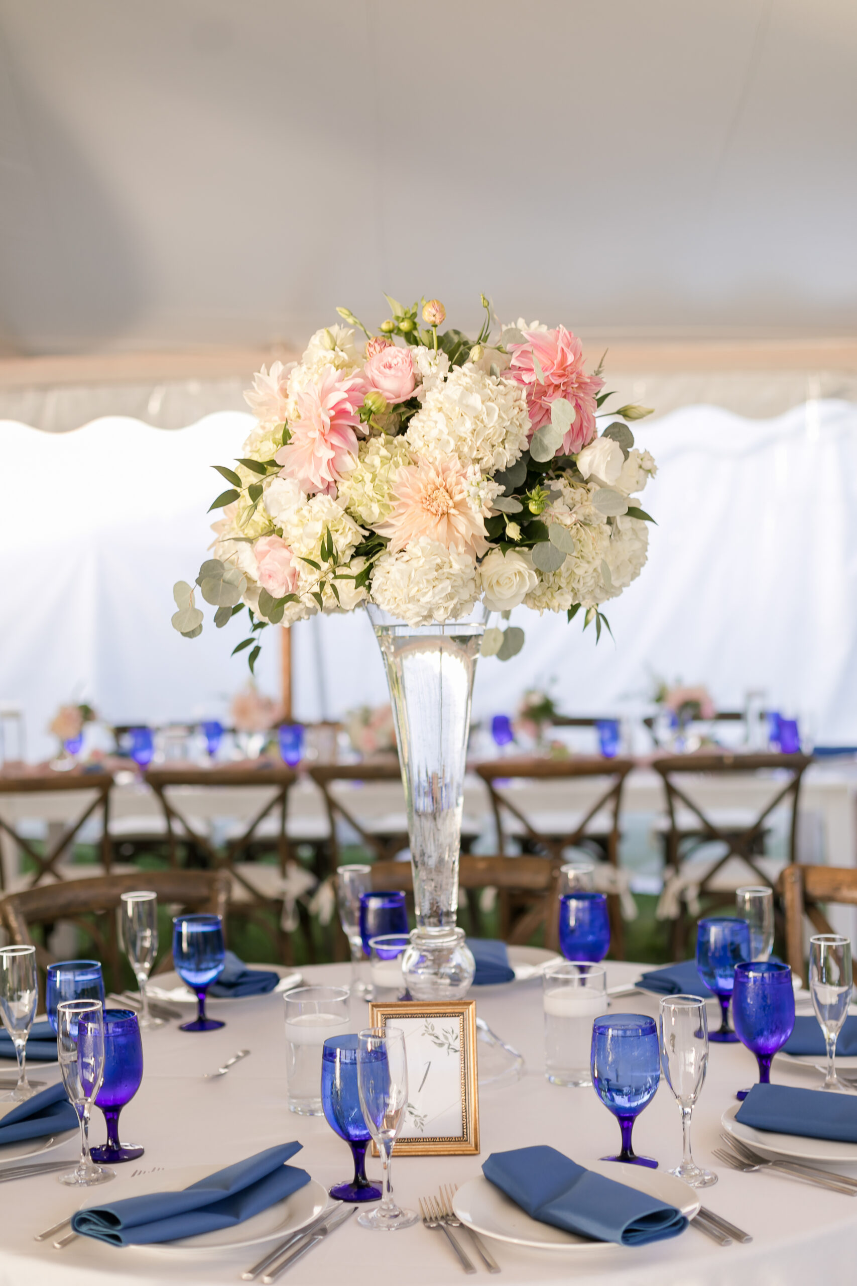 Wedding reception table tall centerpiece with blush pink, cream, and white flowers with accents of greenery