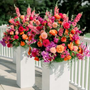 Colorful summer wedding flowers with roses, orchids, and dahlias on tall white pedestals in Boston.