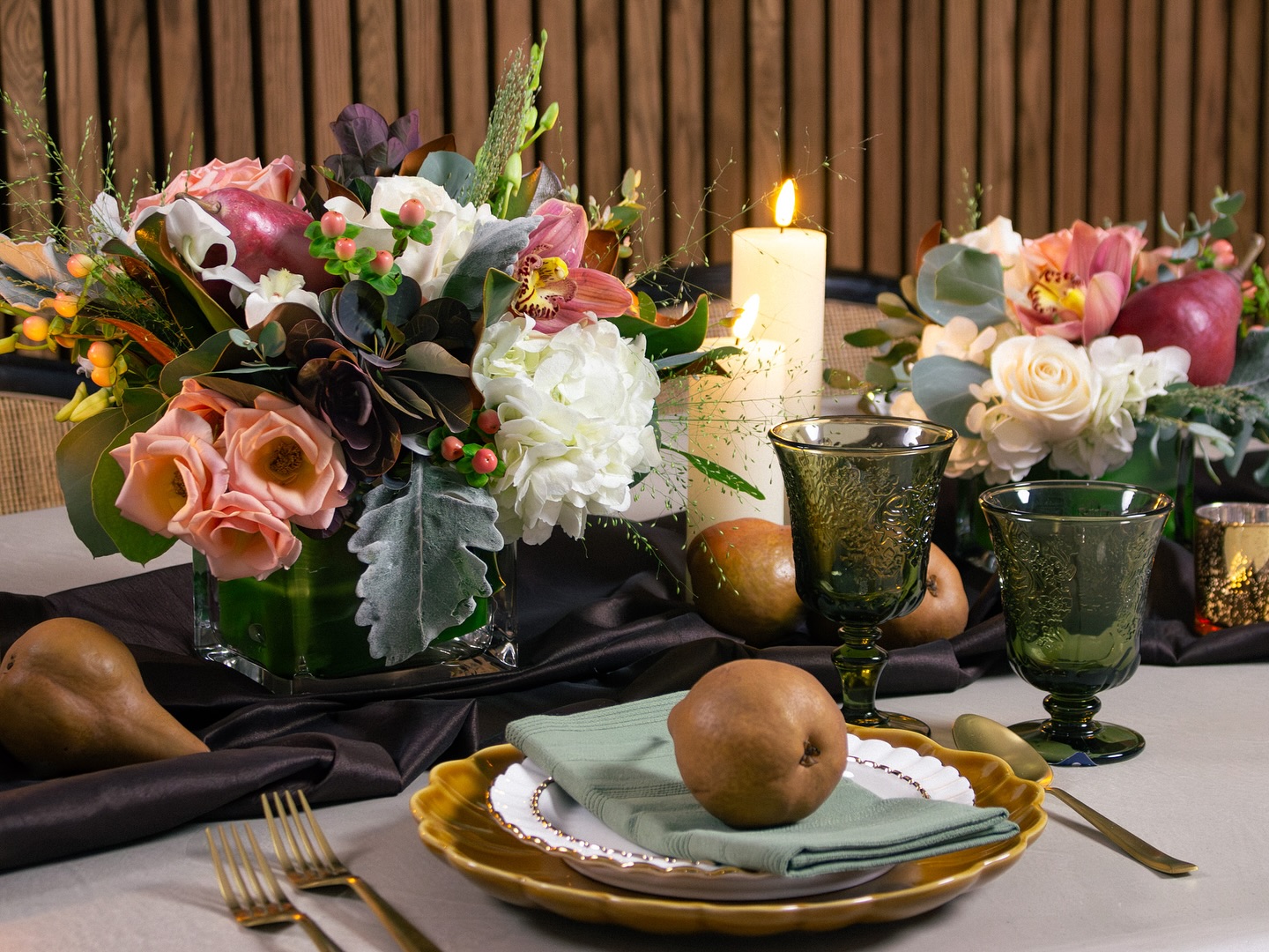 Elegant Thanksgiving table setting featuring a floral arrangement in soft neutrals, candles, and golden dinnerware in a cozy autumn palette.