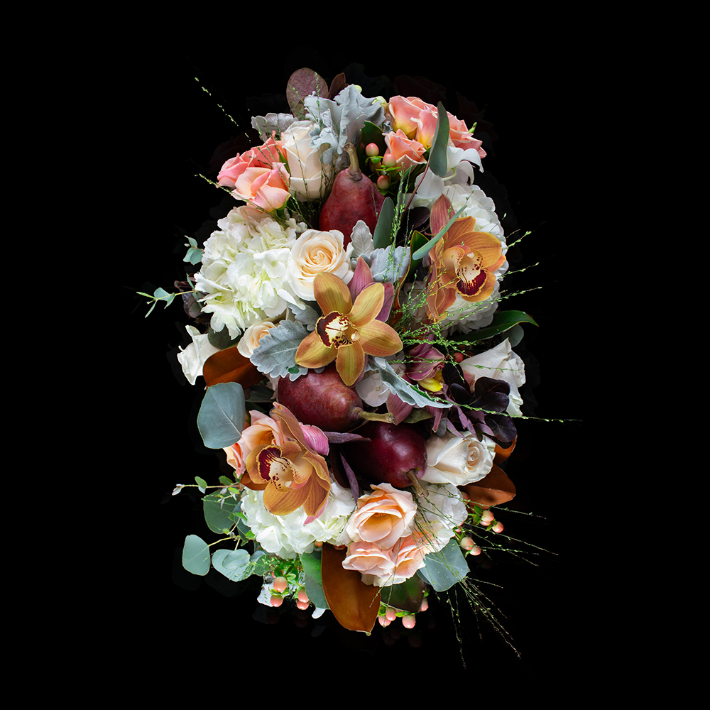 Top view of a Thanksgiving floral arrangement featuring orchids, roses, pears, and seasonal greenery from Stapleton Floral.